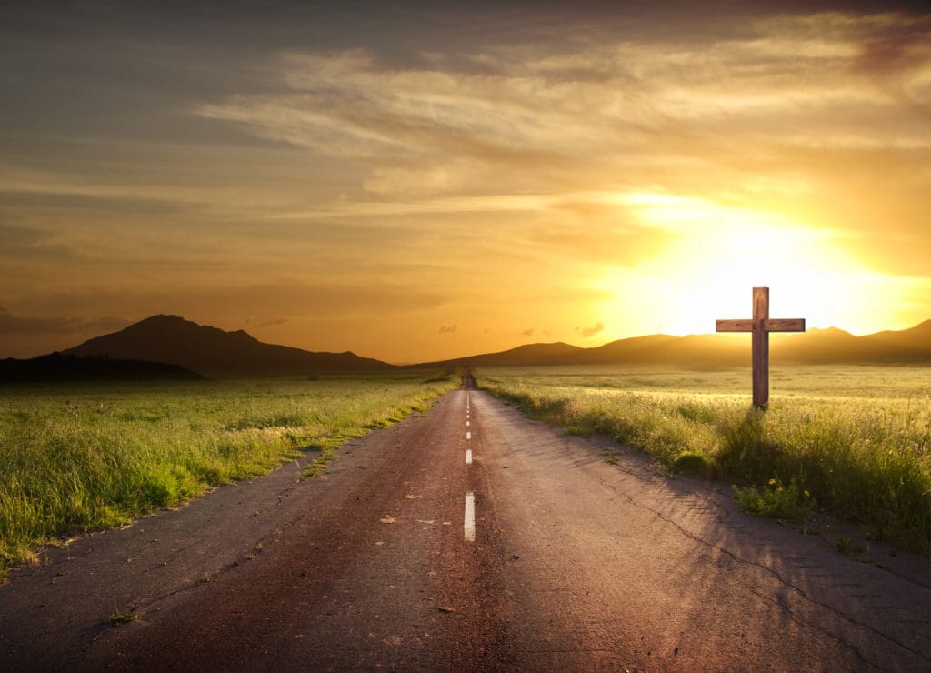 road crosses rural landscape with the silhouette of hill on background the colors of a fiery sunset